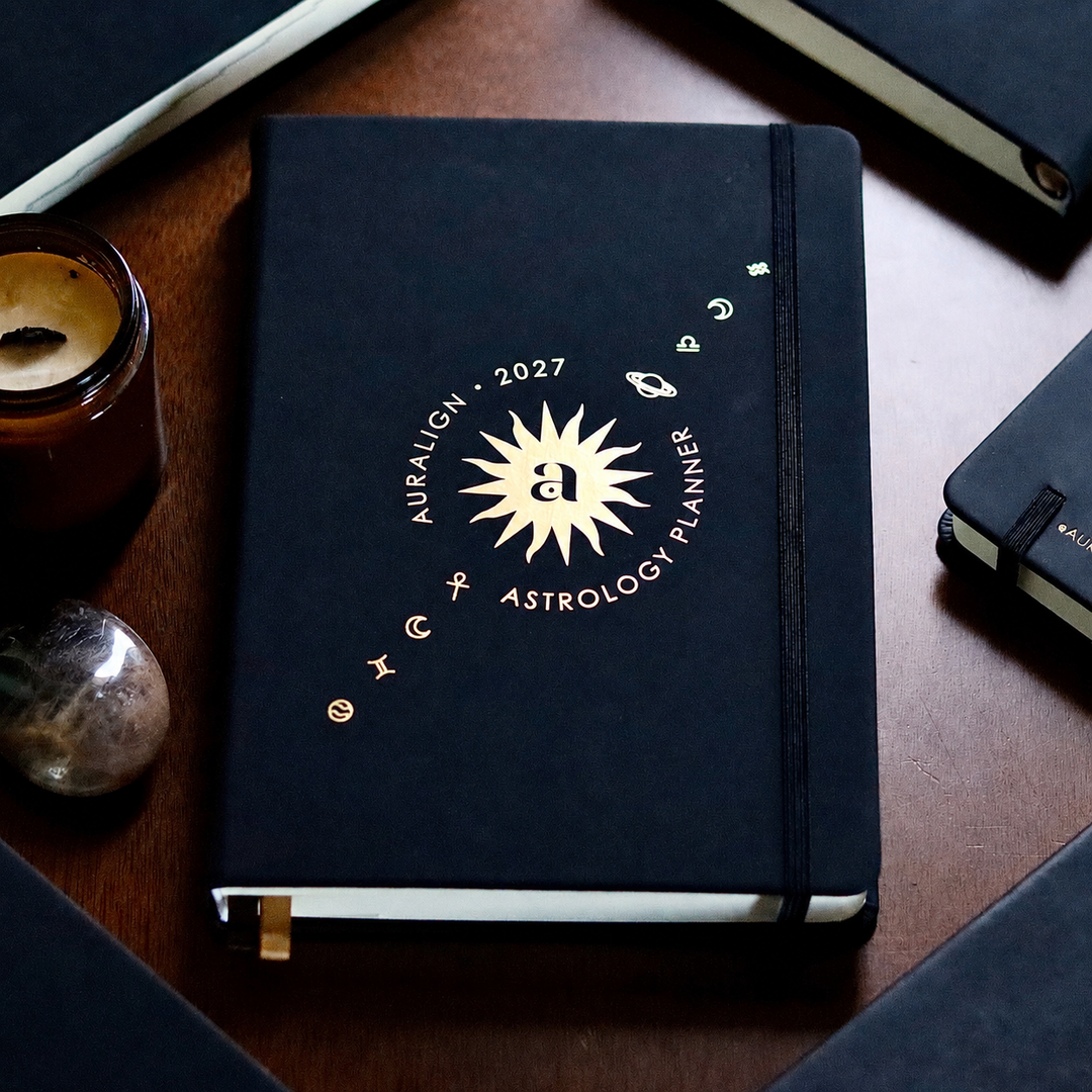 Black astrology planner with gold text on a wooden surface